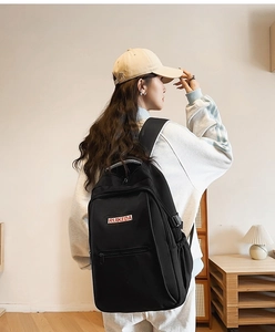 Detail of black canvas backpack with front zipper pocket and adjustable buckles