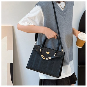 Detail of the black textured leather handbag featuring elegant gold lock hardware