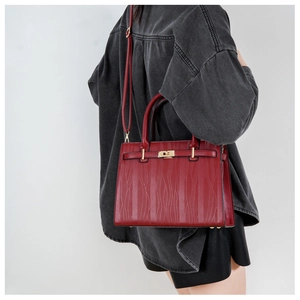 Detailed view of dark red leather handbag with wavy texture and gold lock for women