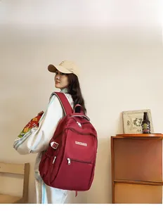 Detail of red nylon backpack with multiple zipper compartments and adjustable side buckle