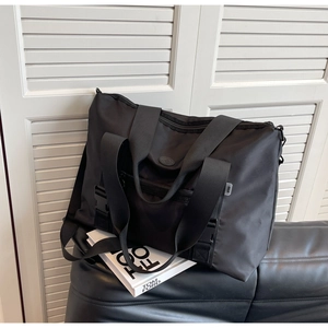 Détail du sac cabas noir en nylon avec poignées durables et bandoulière réglable