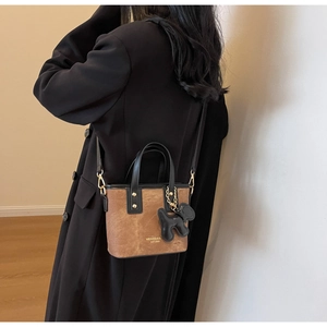 Detail of brown suede bucket bag with black leather trim and cute puppy charm