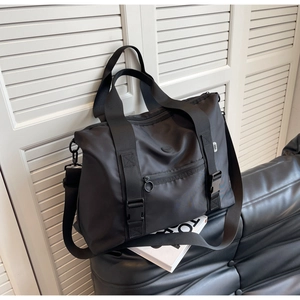 Détail d'un sac de voyage en nylon noir avec doubles poignées et bandoulière réglable