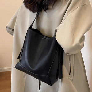 Borsa a secchiello nera minimalista indossata con un trench kaki in luce soffusa