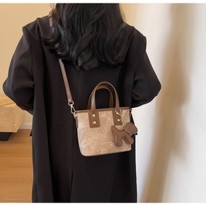Close-up of retro bucket bag in brown leather and beige suede with a cute dog charm