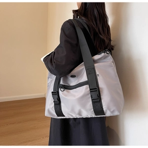 Détail du sac fourre-tout en nylon gris avec poche zippée et fermoirs à boucle de sécurité