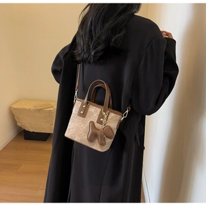 Canvas bucket bag with leather trim shown on model's back as a crossbody style