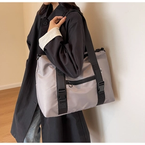 Détail du sac de voyage en nylon gris clair avec sangles noires et boucle de fermeture