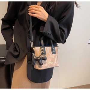 Detail of camel and black mini tote with contrast suede texture and dog charm