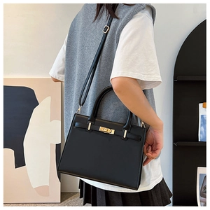 Close-up of elegant black handbag with gold buckle and crossbody strap detail