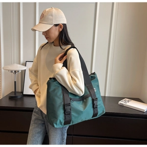 Détail du sac de voyage en nylon vert avec sangles noires et boucle latérale robuste
