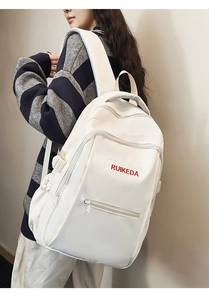 Detail view of Creamy white RUIKEDA backpack with red logo embroidery and multiple pockets