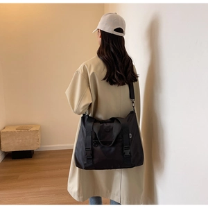 Vue arrière du mannequin portant un grand sac cabas en nylon noir et trench beige