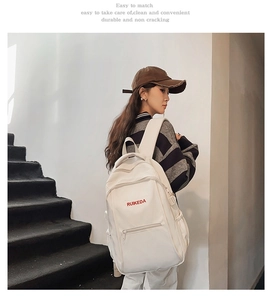 Detail view of large white canvas backpack showing adjustable side buckles and multi-compartments
