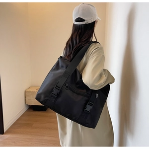 Vue détaillée du sac bandoulière en nylon noir avec doubles boucles et large sangle d'épaule