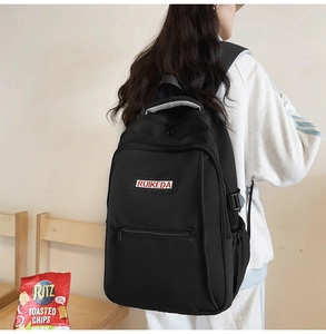 Detail of black nylon backpack featuring RUIKEDA embroidery and breathable mesh straps
