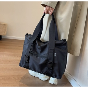 Détail d'un grand cabas en nylon noir avec de larges anses et des boucles de serrage
