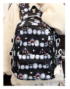 Gros plan du sac à dos noir avec motif de chiot bleu et porte-clé en peluche blanche doux