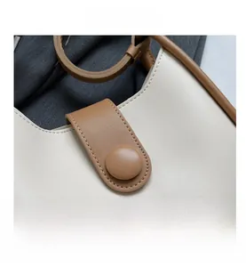 Close-up of beige and brown contrast leather texture with round decorative buckle detail
