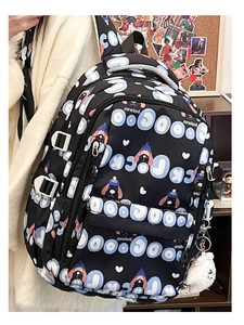 Détail d'un sac à dos noir avec imprimés de chiens bleus et un pendentif en peluche blanc