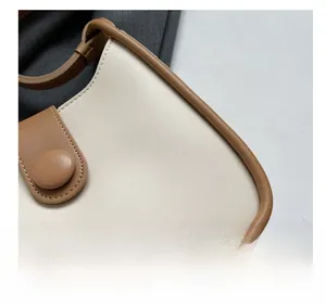 Detailed close-up of beige and brown contrast leather stitching on a stylish bucket bag