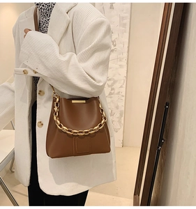 Secchiello marrone caramello con catena dorata indossato da modella in blazer