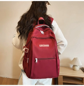 Detailed back view of a burgundy casual backpack with side buckles and logo label