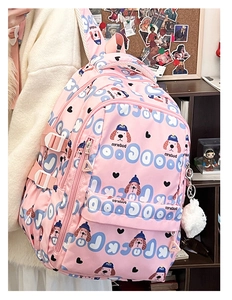 Détail d'un sac à dos rose en toile avec motifs de chiens bleus et porte-clé peluche blanc