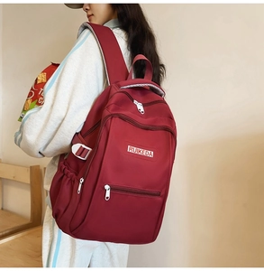 Side view of a burgundy waterproof nylon backpack with multiple zippered compartments