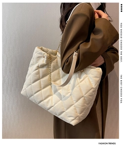 Close-up of quilted white tote bag featuring gold chain straps and nylon texture