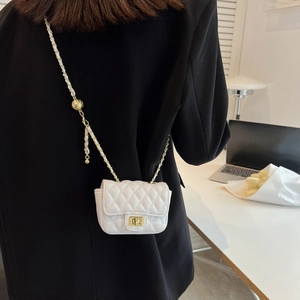 Mini borsa a tracolla bianca trapuntata con catena dorata indossata da modella in completo