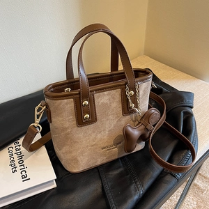 Chic beige and brown leather bucket bag with puppy charm and gold hardware on black leather