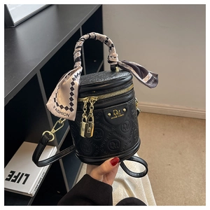 Detailansicht der schwarzen Zylindertasche mit Goldbeschlägen und Seidenschal