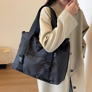 Grand sac fourre-tout en nylon noir avec sangles à boucle porté sur un mannequin en manteau