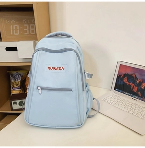 Close-up of light blue nylon backpack with red RUIKEDA embroidery and side bottle pocket
