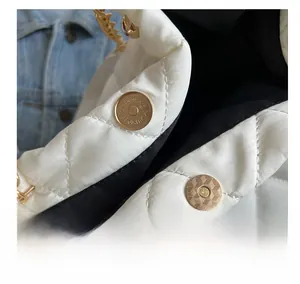 Detail showing the golden magnetic closure and white quilted nylon fabric of the tote bag