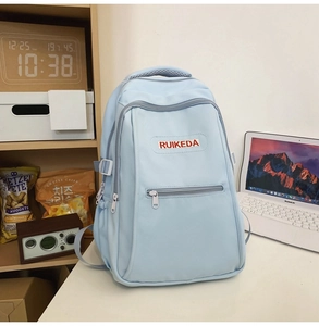 Detail view of water-resistant light blue student backpack with layered zipper pockets