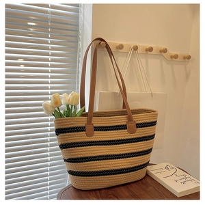 Close-up of woven straw tote bag with black stripes, brown handles and white tulips