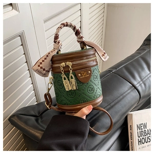 Detailaufnahme der Eimer-Handtasche mit Monogramm-Muster und Seidenschal am Tragegriff