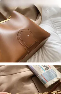 Dettaglio della borsa a secchiello in pelle marrone con trama fine e cuciture decorative
