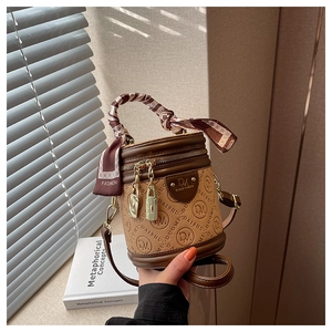 Details einer braunen Monogramm-Beuteltasche mit Seidentuchgriff und Gold-Hardware