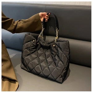 Close-up of quilted nylon tote bag with gold chain strap and spherical hardware detail