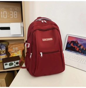 Detail of red nylon backpack with multi-pocket design and contrast white zippers
