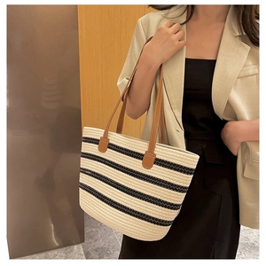Detail of handwoven striped tote bag with premium brown leather handles and stitching