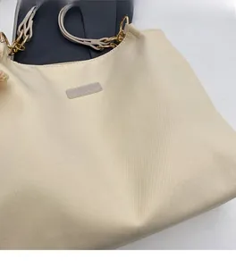 Close-up of cream canvas tote bag with leather strap and golden metal ring details