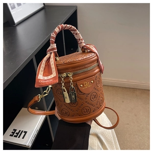 Detail der braunen Eimertasche mit Logo-Prägung, Seidentuch-Griff und goldenem Schloss