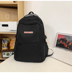 Detailed view of black nylon backpack with brand label on a desk with laptop