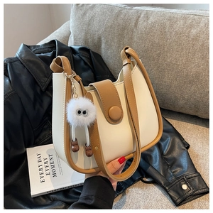 Detail of cream leather crossbody bag with brown trim and cute plush pom-pom charm