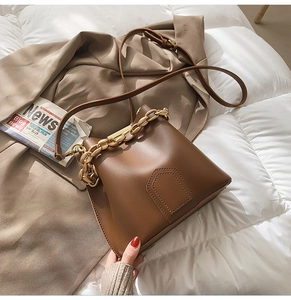 Dettaglio borsa a secchiello in pelle marrone con catena dorata e chiusura magnetica