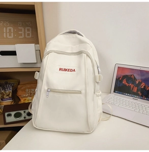 Detailed close-up of white casual backpack with red RUIKEDA embroidery and utility pockets